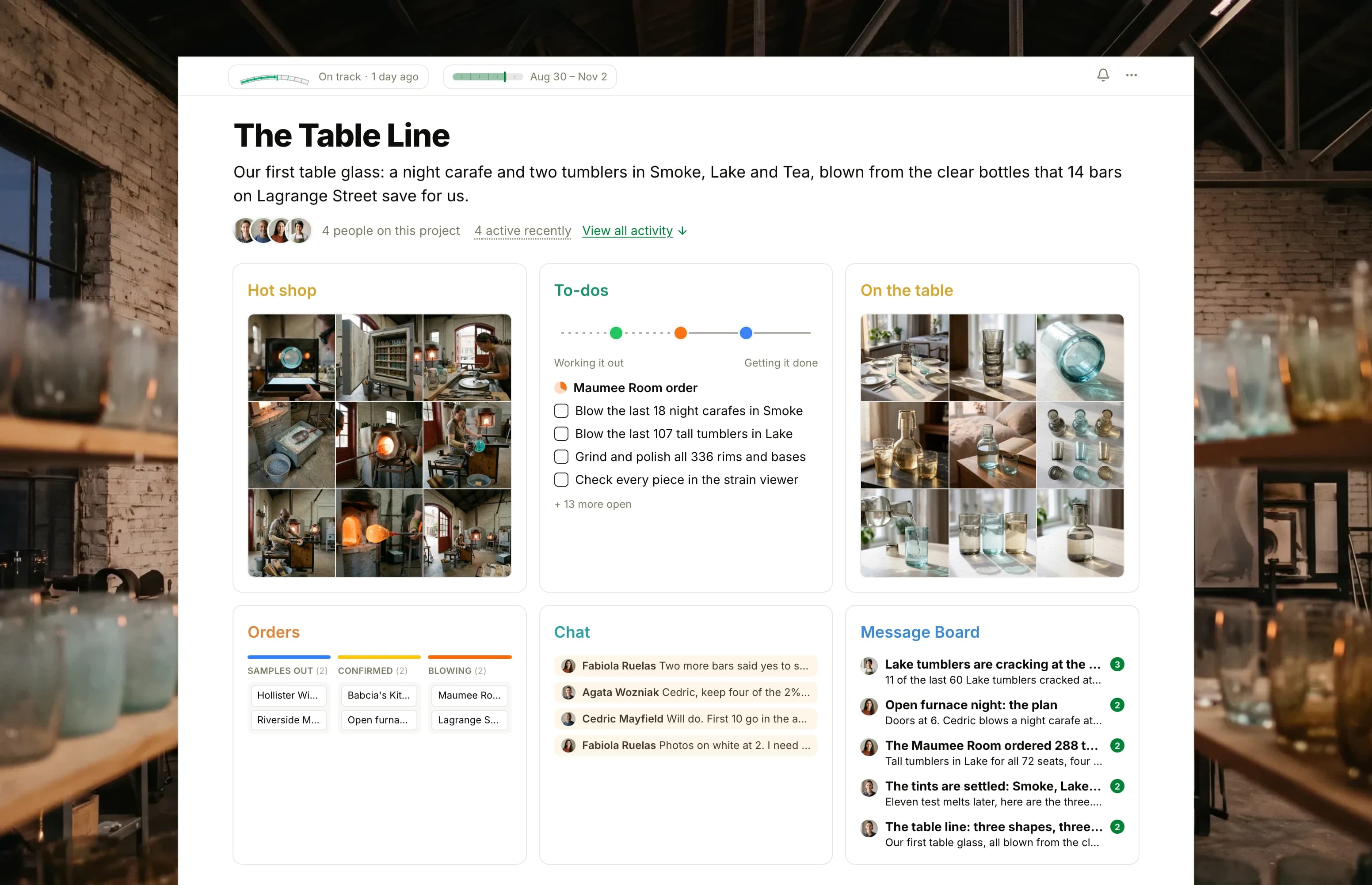 The Table Line project in Thicket over a photograph of a glass furnace glowing in a brick hot shop: the health flag reading On track, the project dates and four people, then six cards: Hot shop as nine photographs of glassblowing at the furnace and the bench, To-dos with three lists on the progress chart, On the table as nine photographs of the carafe and tumblers in gray, blue-green and brown, the Orders board with cards from Samples out to Cold shop, Chat with the morning's furnace and annealer news, and the Message Board with the cracking Lake tumblers on top.